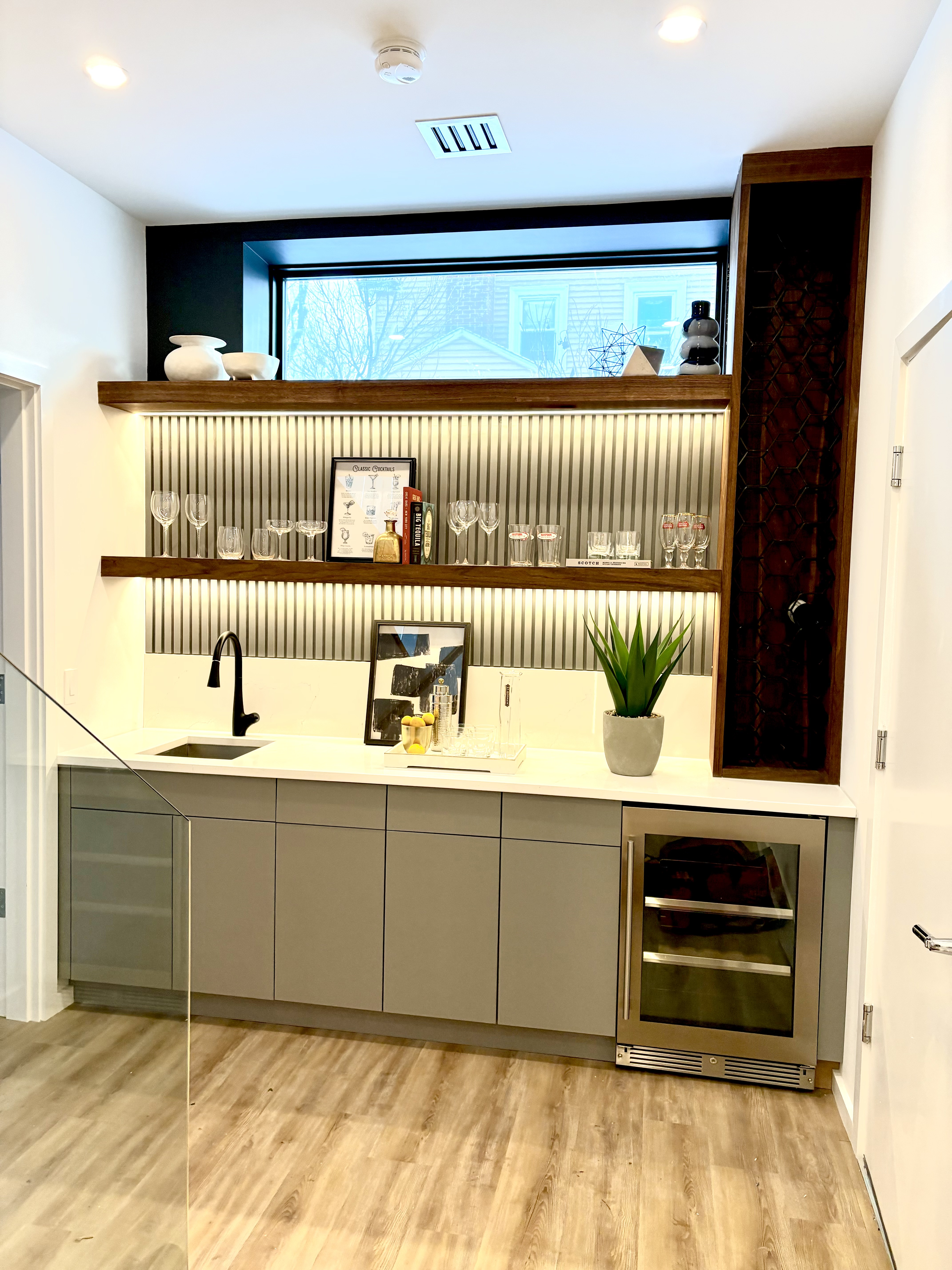 Wood cabinets with colored marble backsplash and countertop, and a built-in desk nook with glass cabinet doors