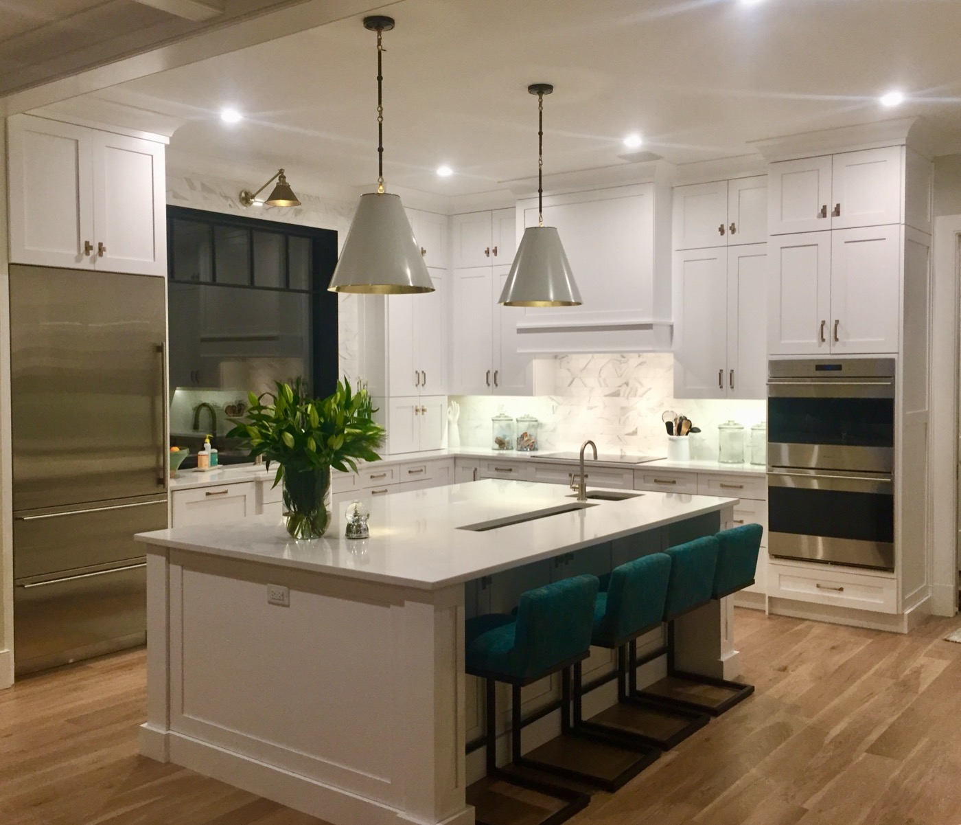 White kitchen with tile backsplash, pendant lights, and stools
