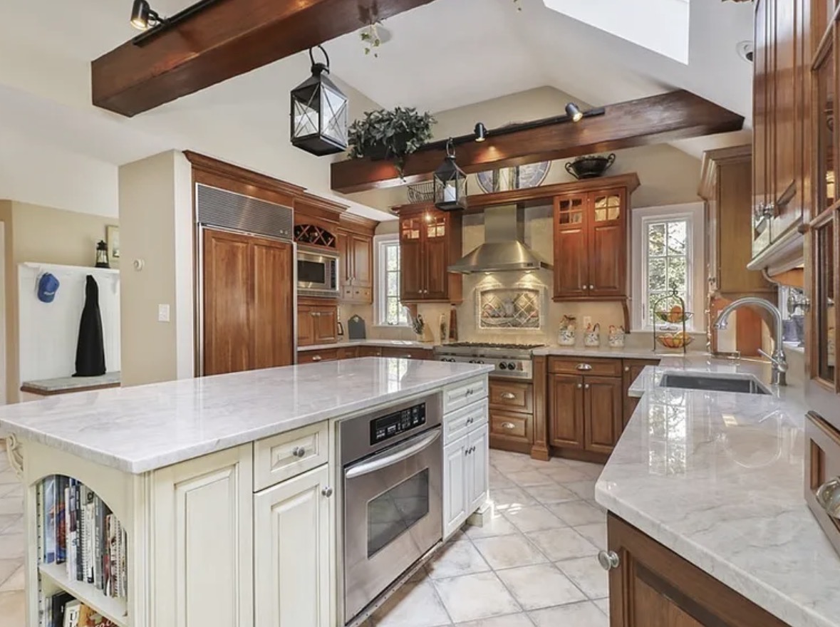Second image of kitchen with white table, wood cabinets and black appliances